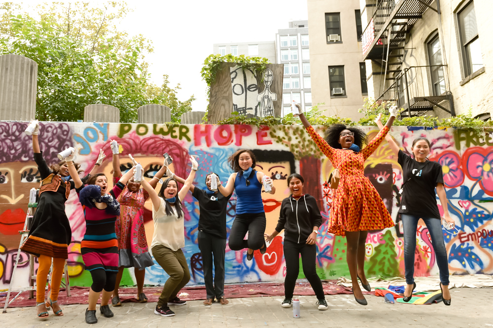 Group jumping in front of a painted community mural at a nonprofit event